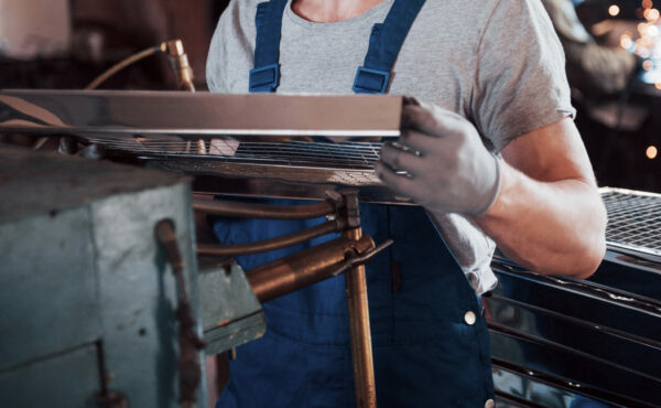 Portrait of a young worker in a hard hat at a large waste recycling factory. The engineer monitors the work of machines and other equipment.